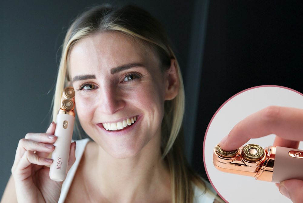 Lächelnde Frau hält den Roxy Body & Shave Damenrasierer an ihr Gesicht - Detail von Doppel-Rasierköpfe
